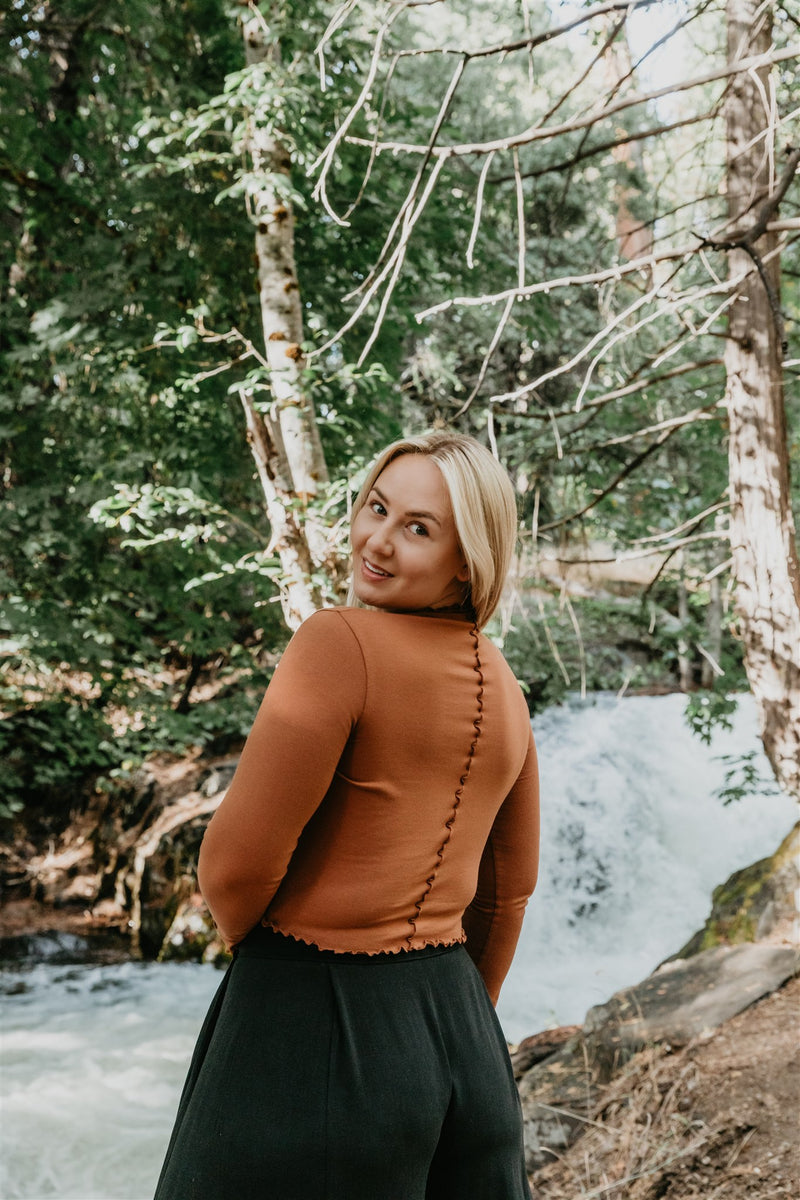 Woman standing in a forest with a waterfall in the background