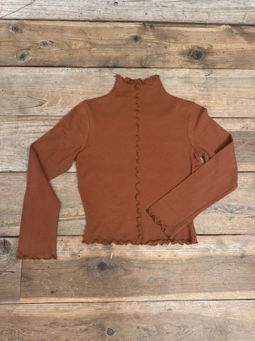 Brown blouse with ruffled details on a wooden surface